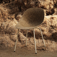 Brown speckled chair with a smooth, curved seat and white metal legs, set against a rustic, textured backdrop.