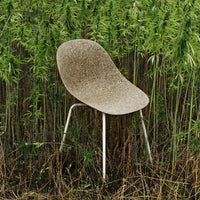Natural beige chair with a smooth, curved surface, set against vibrant green bamboo background.