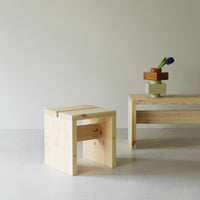 Light natural wood stool with clean lines, paired with a simple wood bench and colorful geometric decor.