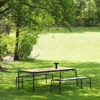 Outdoor table and benches featuring a natural wood finish with sleek black metal accents, set on lush green grass.