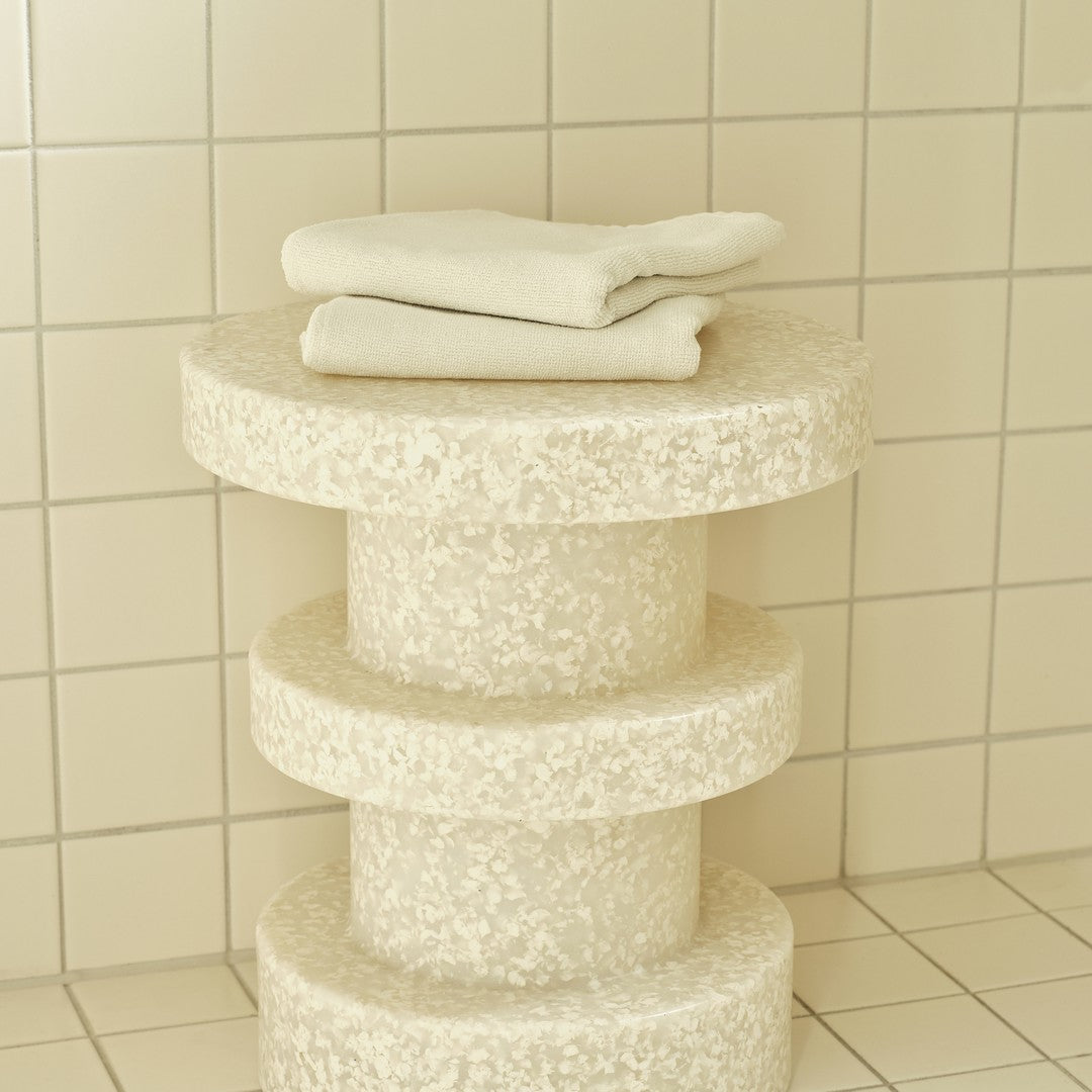 Stylish creamy white three-tier stool with a textured finish, featuring neatly stacked white towels.