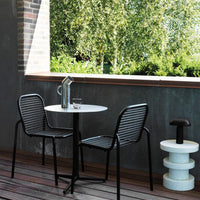 Black and white striped chairs paired with a round white table, set against a lush green background.