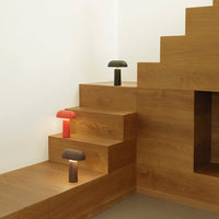 Three stylish lamps in red, black, and brown atop wooden stairs, enhancing modern decor with a pop of color.