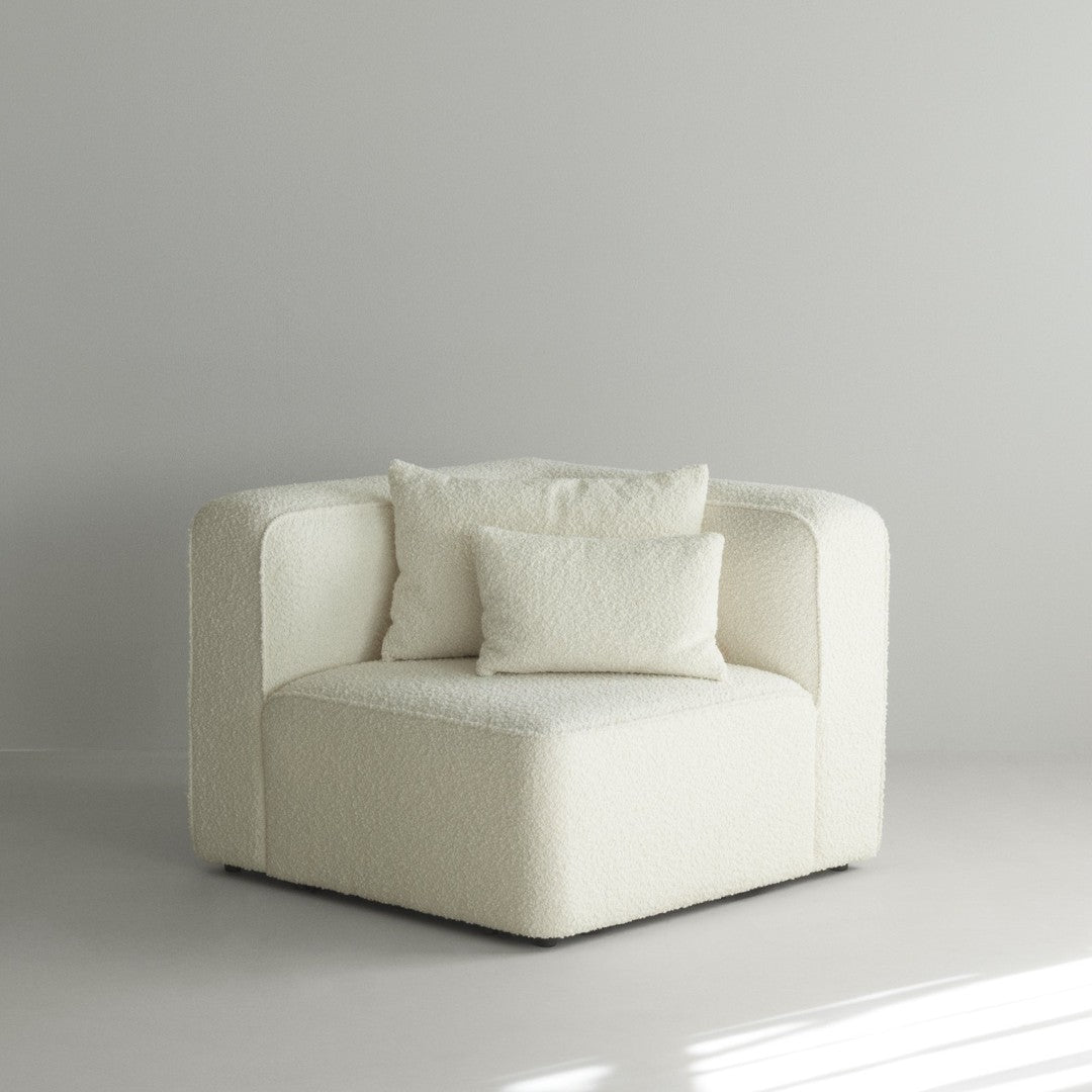Cream-colored, plush armchair with soft texture and matching decorative pillows, perfect for modern interiors.
