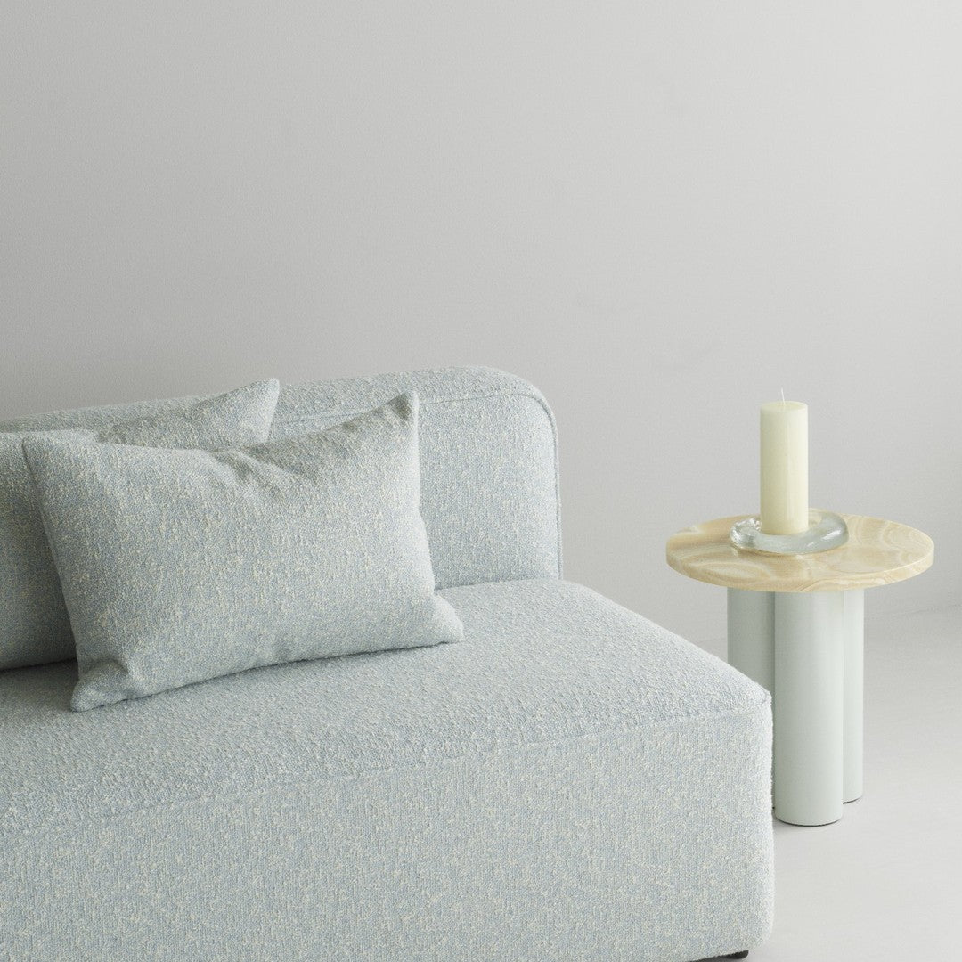 Soft blue textured sofa with light gray accents and decorative pillows, featuring a natural wood side table.