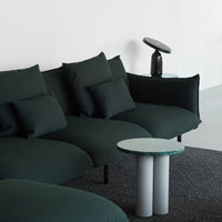 Dark green upholstered sofa with textured cushions, paired with a light gray and green marble side table on a black textured rug.