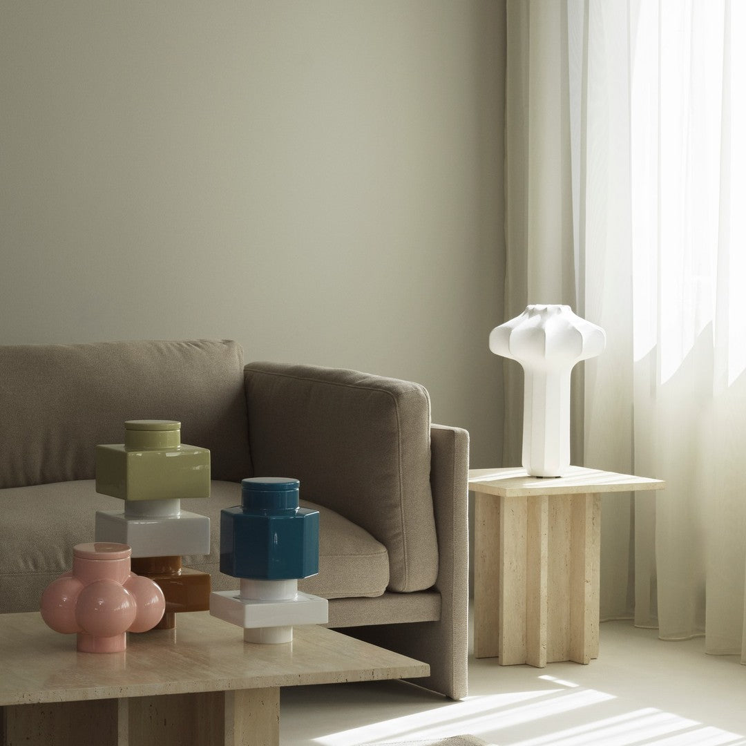 Colorful ceramic vases in green, blue, pink, and white, arranged on natural wood tables in a modern living space.