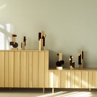 Wooden decorative sculptures in warm oak and rich dark brown, showcasing geometric shapes on a light background.