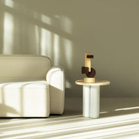 Beige sofa with soft texture, circular wood and white table with geometric wooden sculpture, neutral color palette.