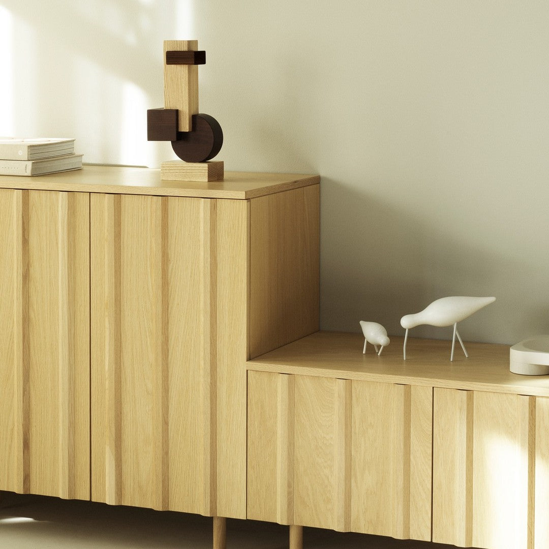 Light wood grain cabinet with minimalist geometric shapes in natural tones, featuring white decor accents.