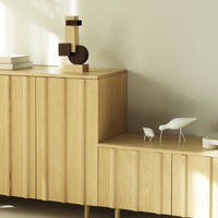 Light wood grain cabinet with minimalist geometric shapes in natural tones, featuring white decor accents.