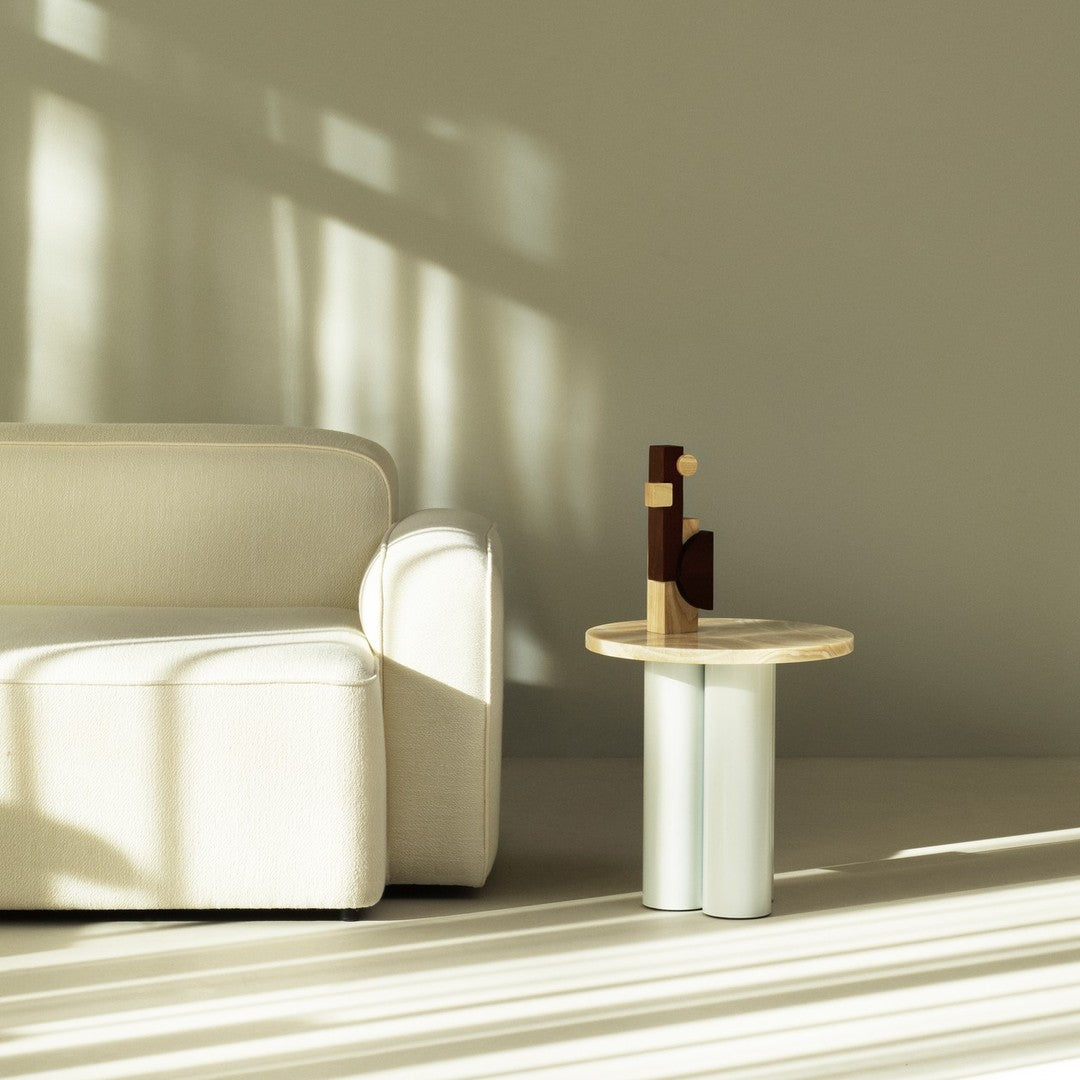 Minimalist living room featuring a cream couch, light wood table, and earthy tones, with soft shadows and textures.