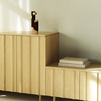 Wooden furniture featuring light oak finish, vertical slats, and subtle natural textures, accented by geometric decor.