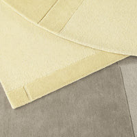 Textured rugs in soft yellow and muted gray colors, featuring a blend of smooth and plush patterns.