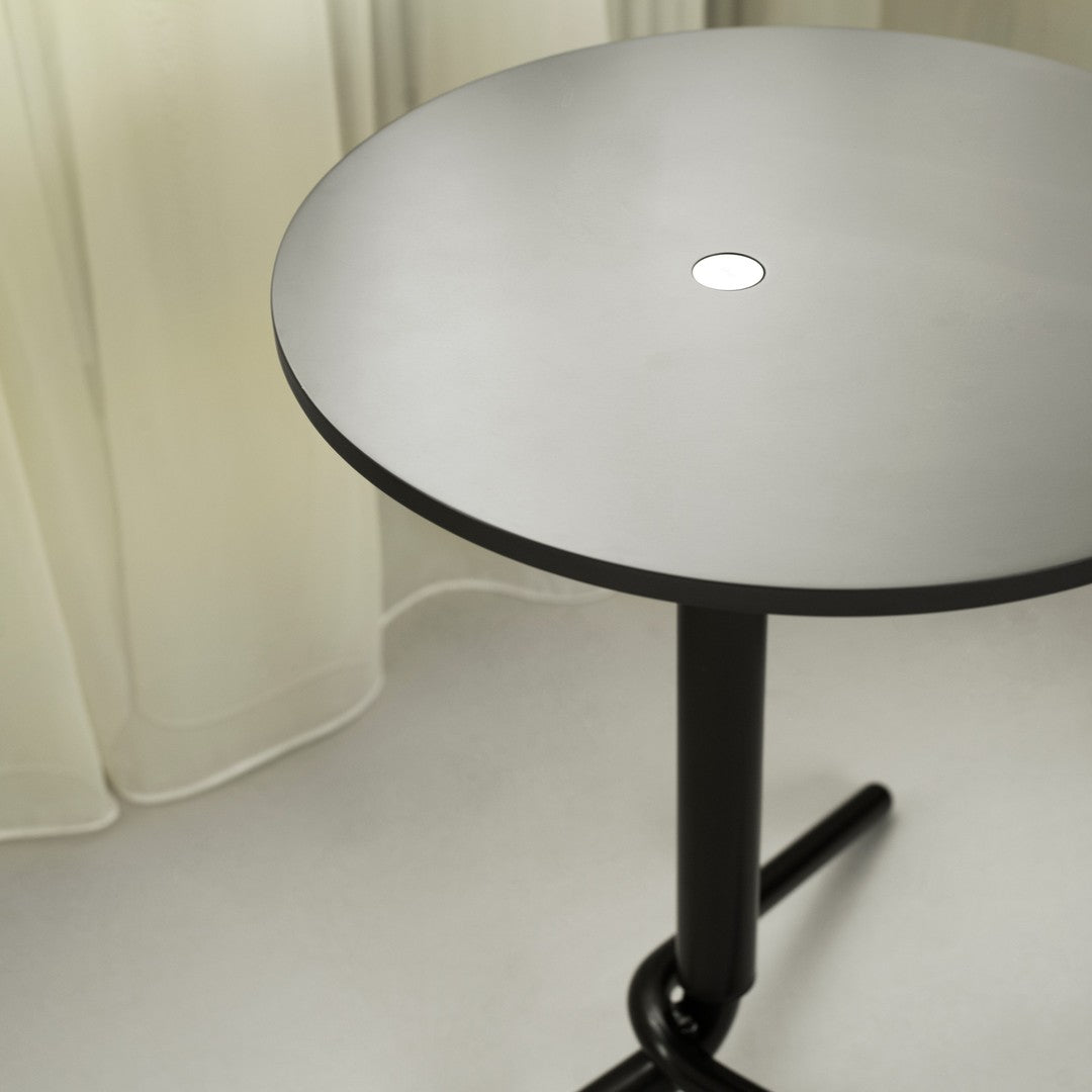 Modern round table with a sleek matte black base and a light gray top featuring a minimalist design.