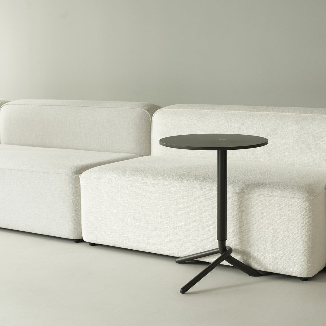 Black side table next to soft, white sectional sofa against a neutral wall, creating a modern, minimalist aesthetic.