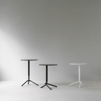 Three modern side tables in black and white, featuring sleek circular tops and tripod bases against a neutral background.