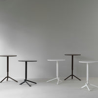 Set of modern tables in brown, black, and white with sleek, minimalist designs against a light gray background.