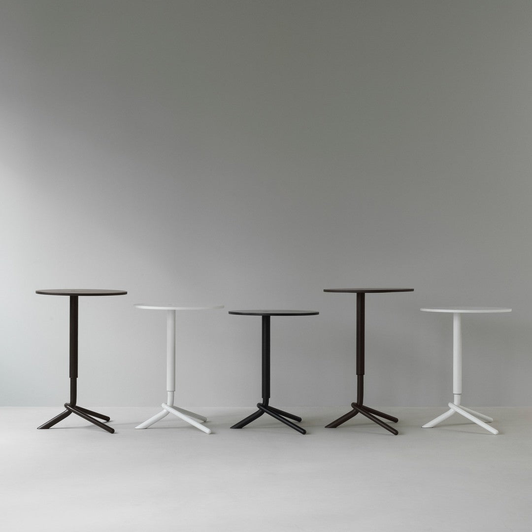 Set of four modern side tables in black, white, and dark brown, featuring sleek round tops and minimalist designs.