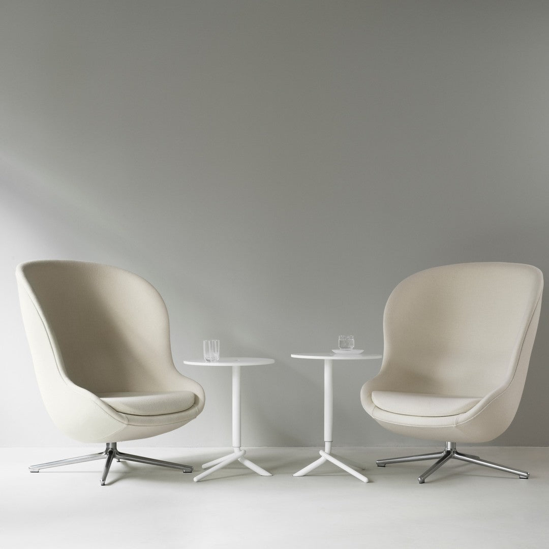 Beige upholstered chairs with white tables against a light gray wall, minimalistic and modern design.