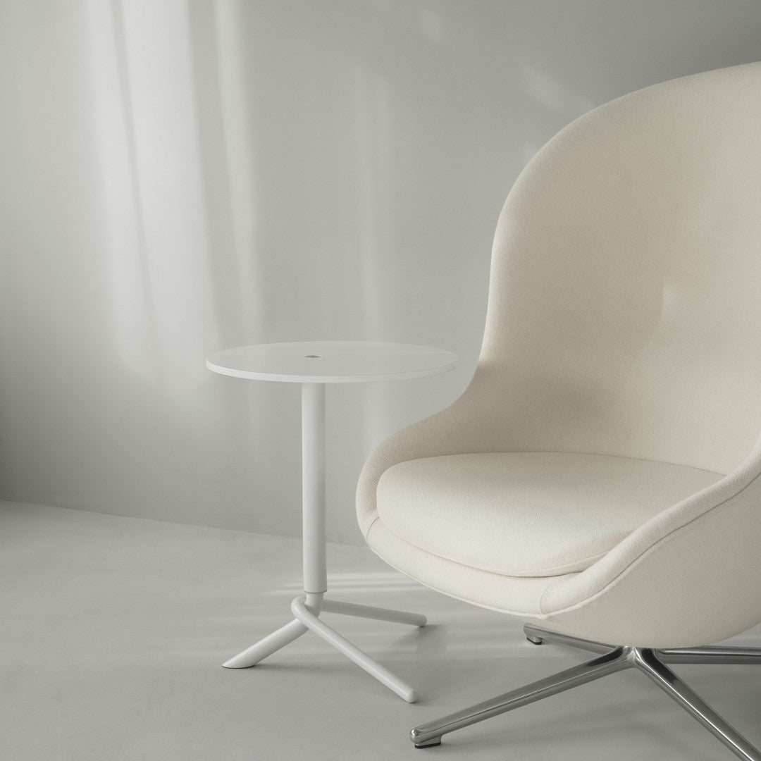 Minimalist white armchair and side table, featuring soft beige upholstery and sleek metallic accents against a light gray background.