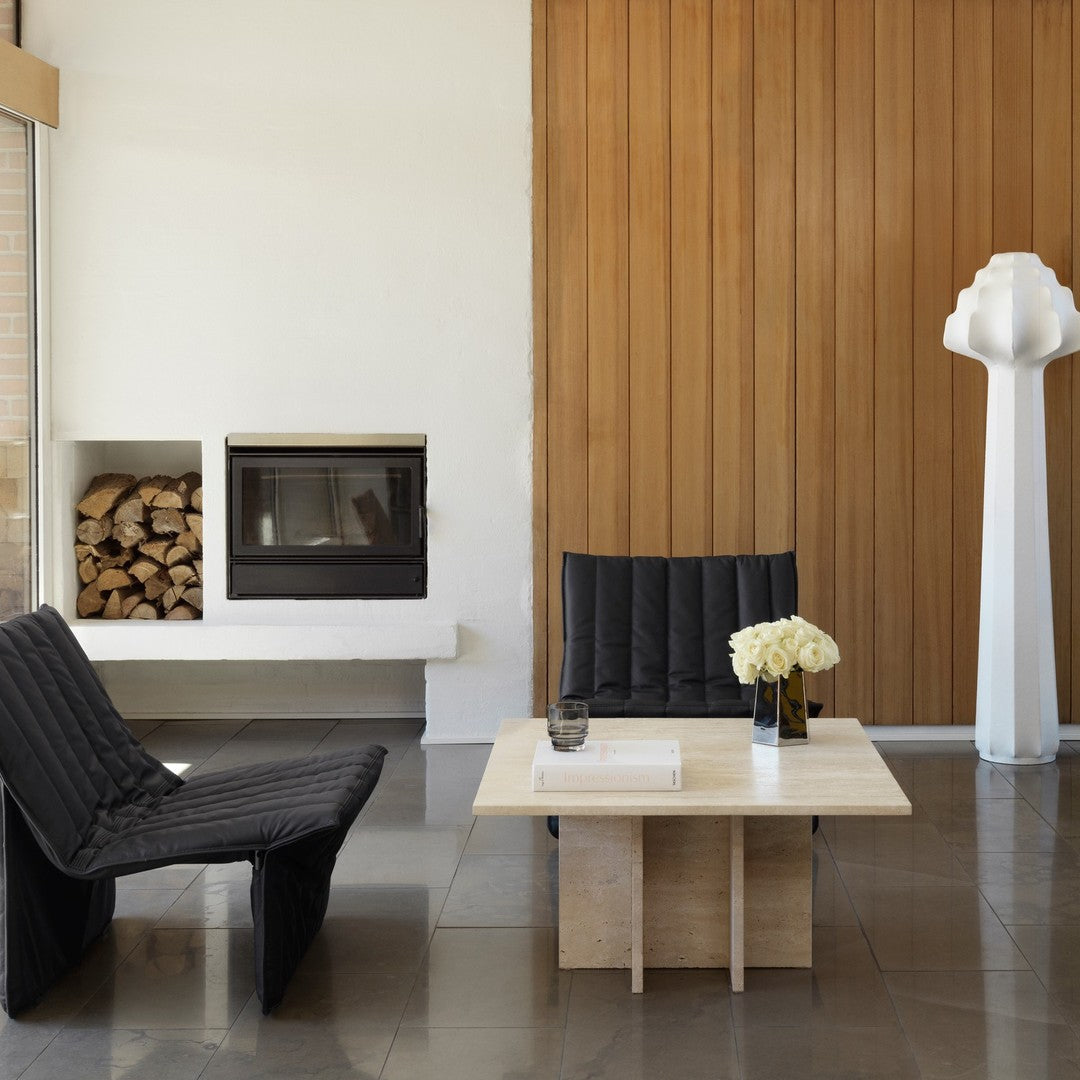 Two sleek black upholstered chairs with a quilted pattern, paired with a minimalist light wood coffee table.
