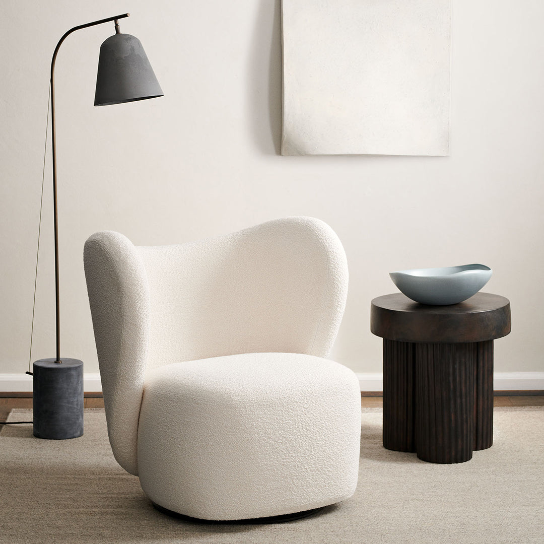 Cozy cream accent chair with soft, rounded shapes against a neutral backdrop, complemented by dark wood and gray accents.
