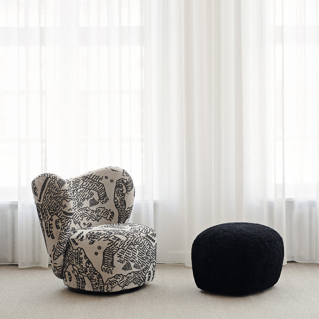 Textured black and white patterned armchair with a matching black pouf in a bright, airy setting.