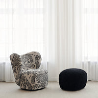 Textured black and white patterned armchair with a matching black pouf in a bright, airy setting.