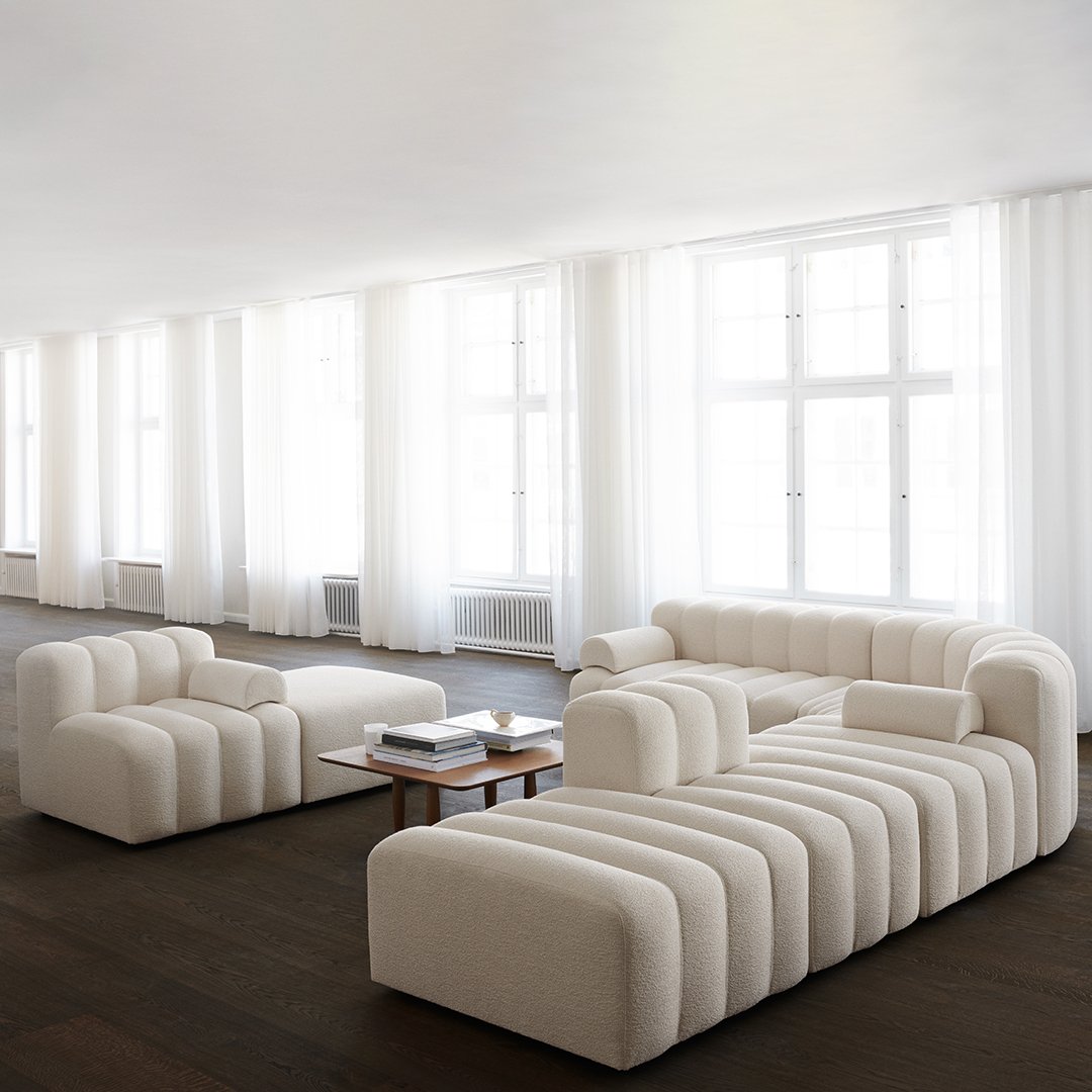 Cream-colored modular sofa with soft, curved lines and minimalistic design, set in a bright, airy space.
