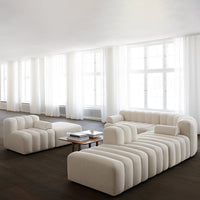 Cream-colored modular sofa with soft, curved lines and minimalistic design, set in a bright, airy space.