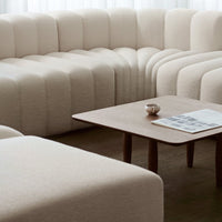 Beige boucle fabric sectional sofa with a modern ribbed pattern, complemented by a minimalist wooden coffee table.