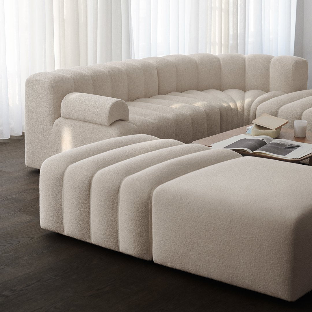 Beige curved sectional sofa with horizontal ribbed pattern, creating a soft, modern aesthetic for any living space.