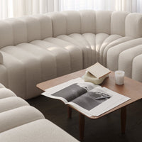 Textured cream-colored sectional sofa with rounded lines and subtle patterns, paired with a warm wooden coffee table.