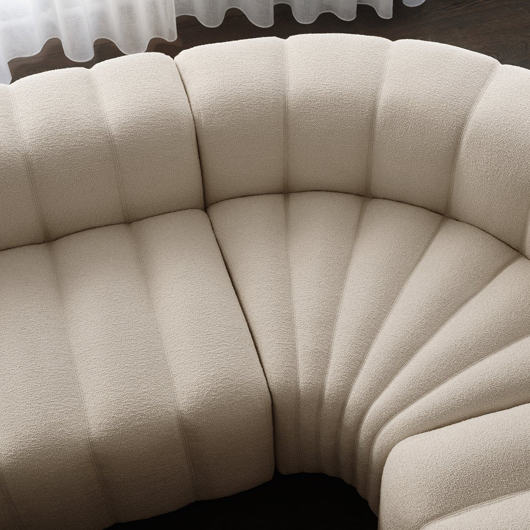 Cream-colored curved couch with plush, ribbed texture and subtle vertical lines.