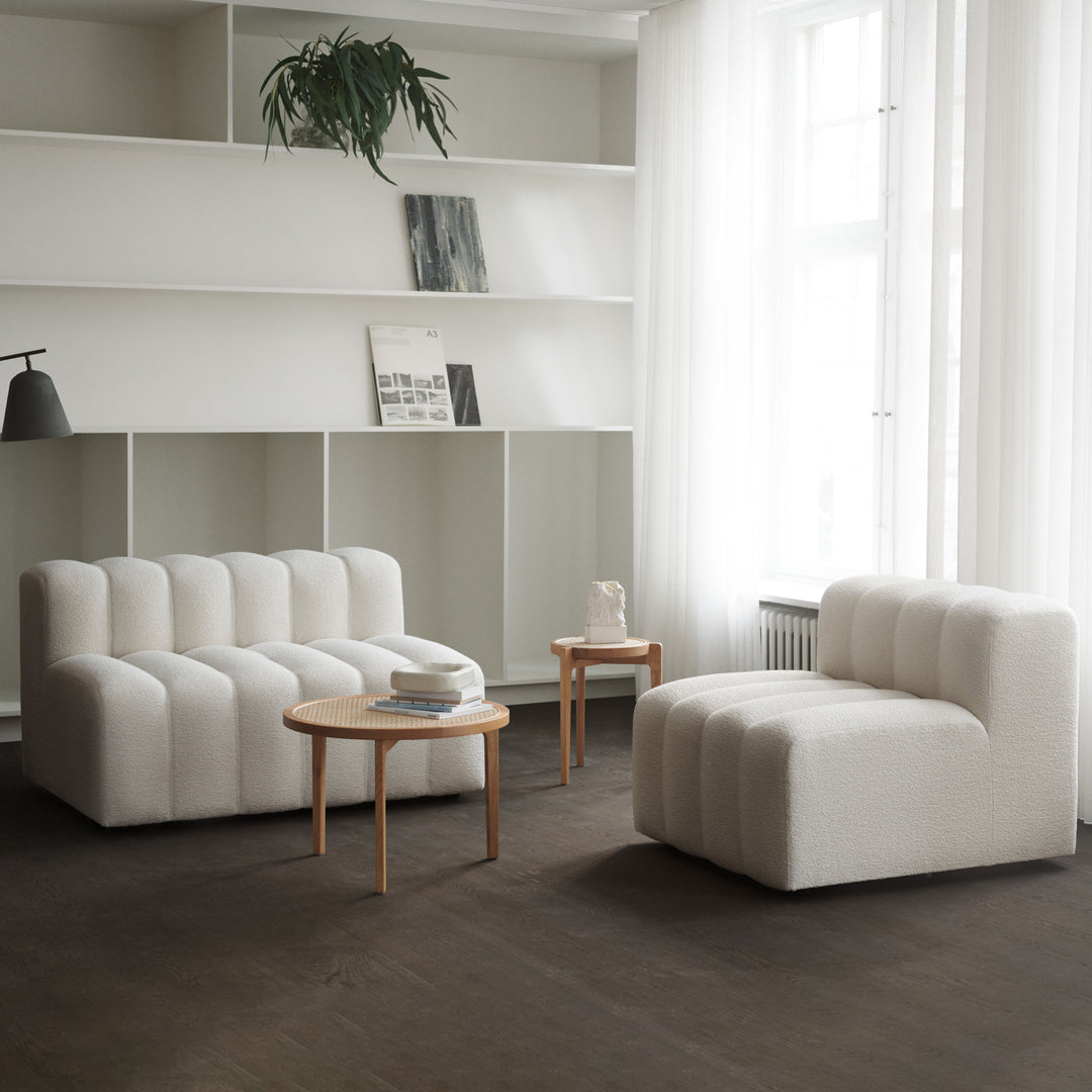 Soft white tufted chairs in a minimalist living room with neutral tones and natural wood accents.