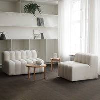Soft white tufted chairs in a minimalist living room with neutral tones and natural wood accents.