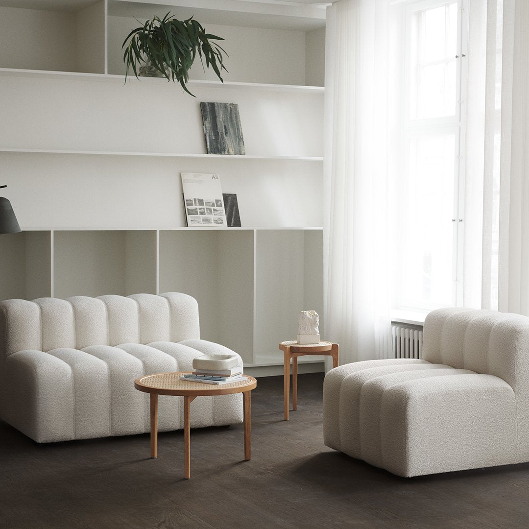 White textured sofas with ribbed patterns, complemented by light wood accents and a minimalist decor setting.