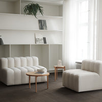 White textured sofas with ribbed patterns, complemented by light wood accents and a minimalist decor setting.