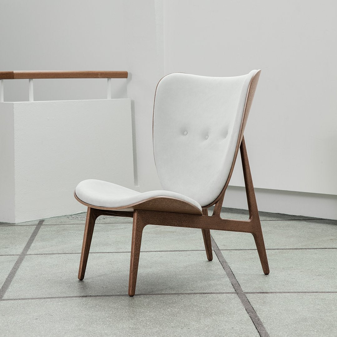 White upholstered chair with tufted design and natural wood legs, featuring a sleek, modern aesthetic.