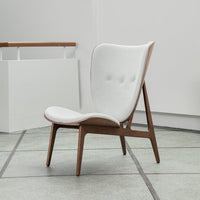 White upholstered chair with tufted design and natural wood legs, featuring a sleek, modern aesthetic.