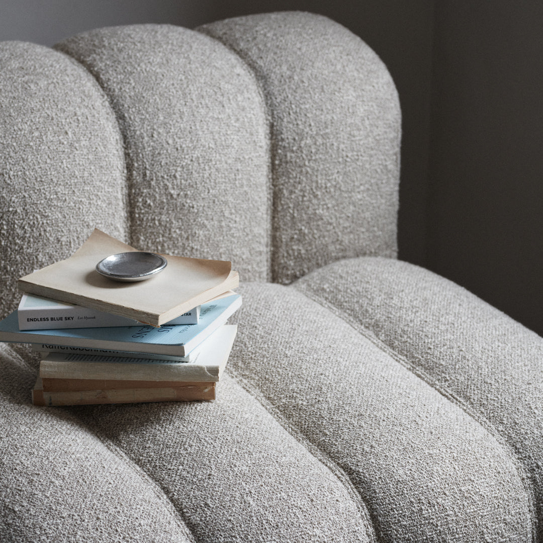 Textured beige upholstery on a curved chair, featuring soft, neutral tones with a hint of warmth.