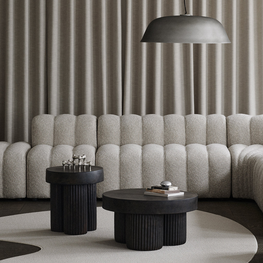 Black and gray furniture set against textured beige upholstery and soft gray curtains. Minimalist modern design.