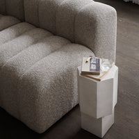 Textured light gray sofa with soft, tufted upholstery and a minimalist white side table.