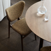Stylish brown patterned chair next to a round wooden table, featuring a warm, textured upholstery.