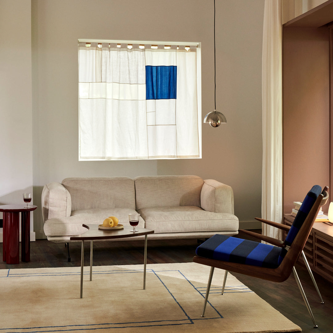 "Elegant beige sofa with blue and white patterned curtains and a striped blue chair in a warm, modern living room."