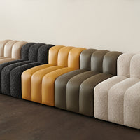 Modern sectional sofa featuring curved, striped patterns in gray, yellow, olive green, beige, and cream tones.