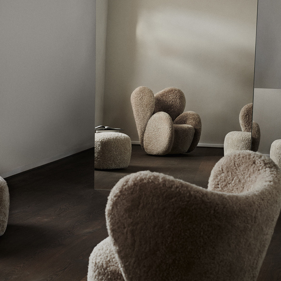 Soft beige and cream upholstered chairs with rounded, organic shapes, set against a neutral background.