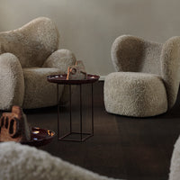 Cozy beige textured armchairs with rounded shapes, set on dark wooden flooring, complemented by a sleek table.