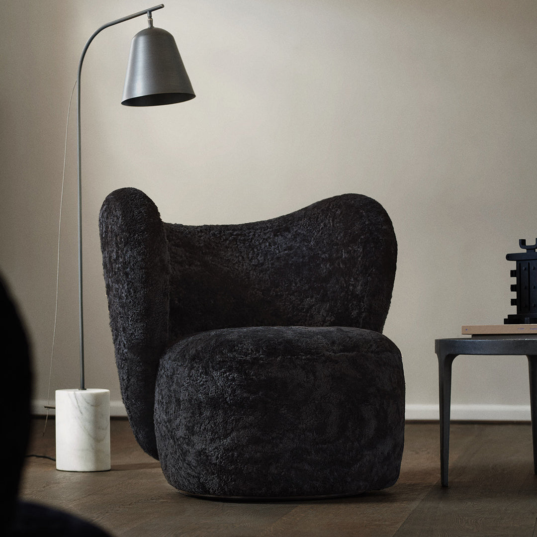 Plush black upholstered chair with a unique, curvy design, set against a neutral backdrop for modern aesthetics.